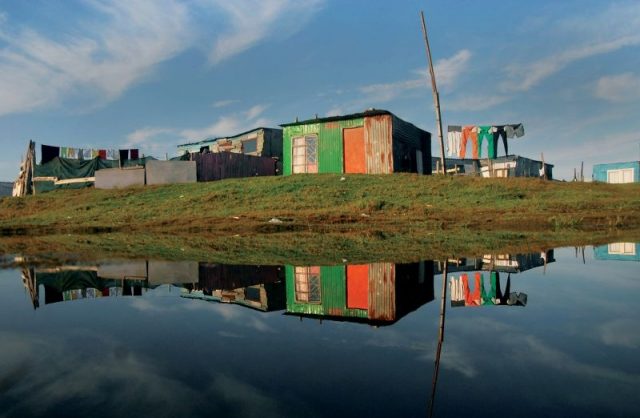 Masixole Feni Cape Town: A pool of water reflecting shack houses after a heavy rain over the Weekend, in Mfuleni Informal Settlement, 2015